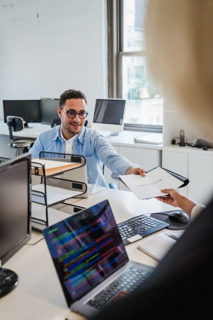 Two office colleagues exchanging documents at work