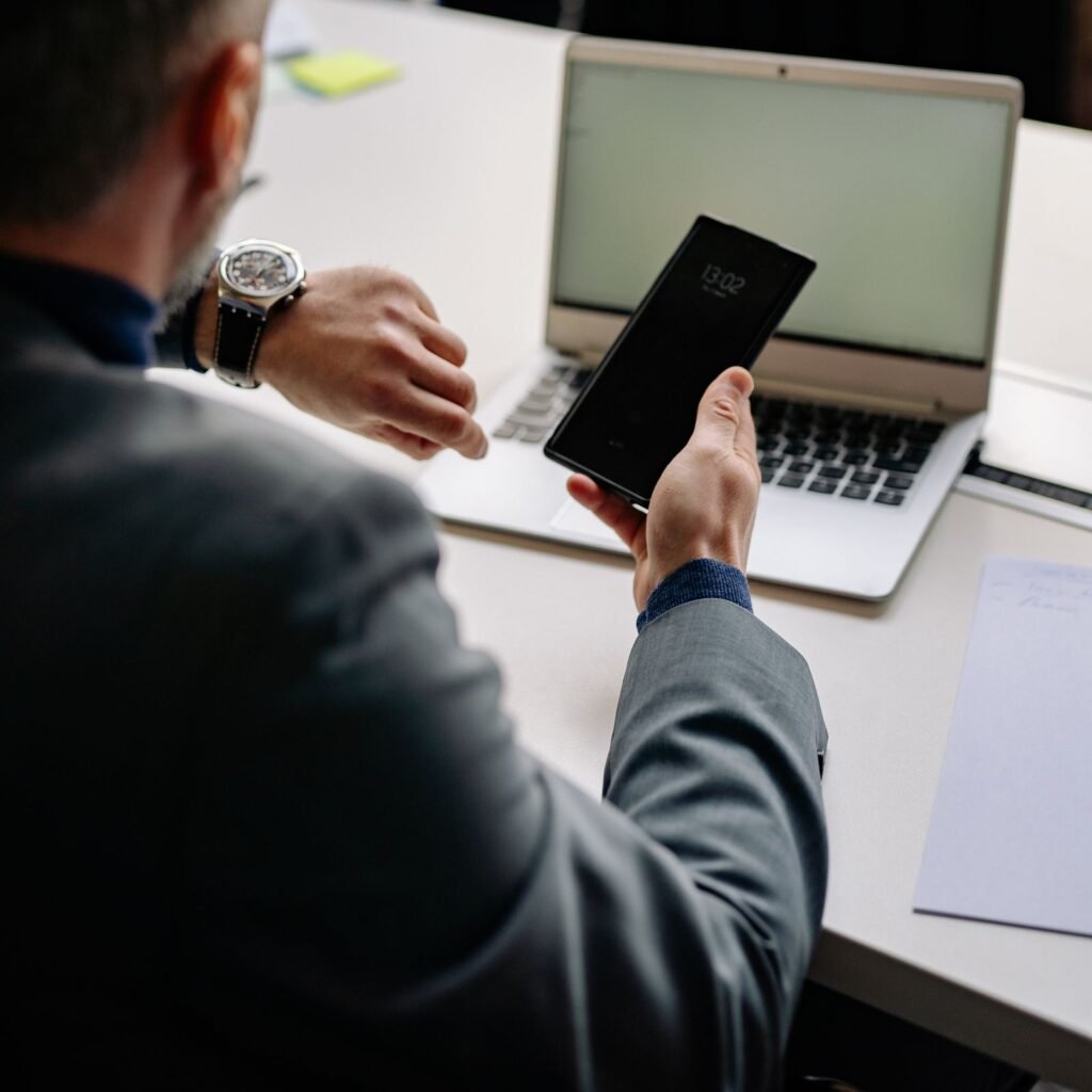 Office worker using a smartphone next to a laptop